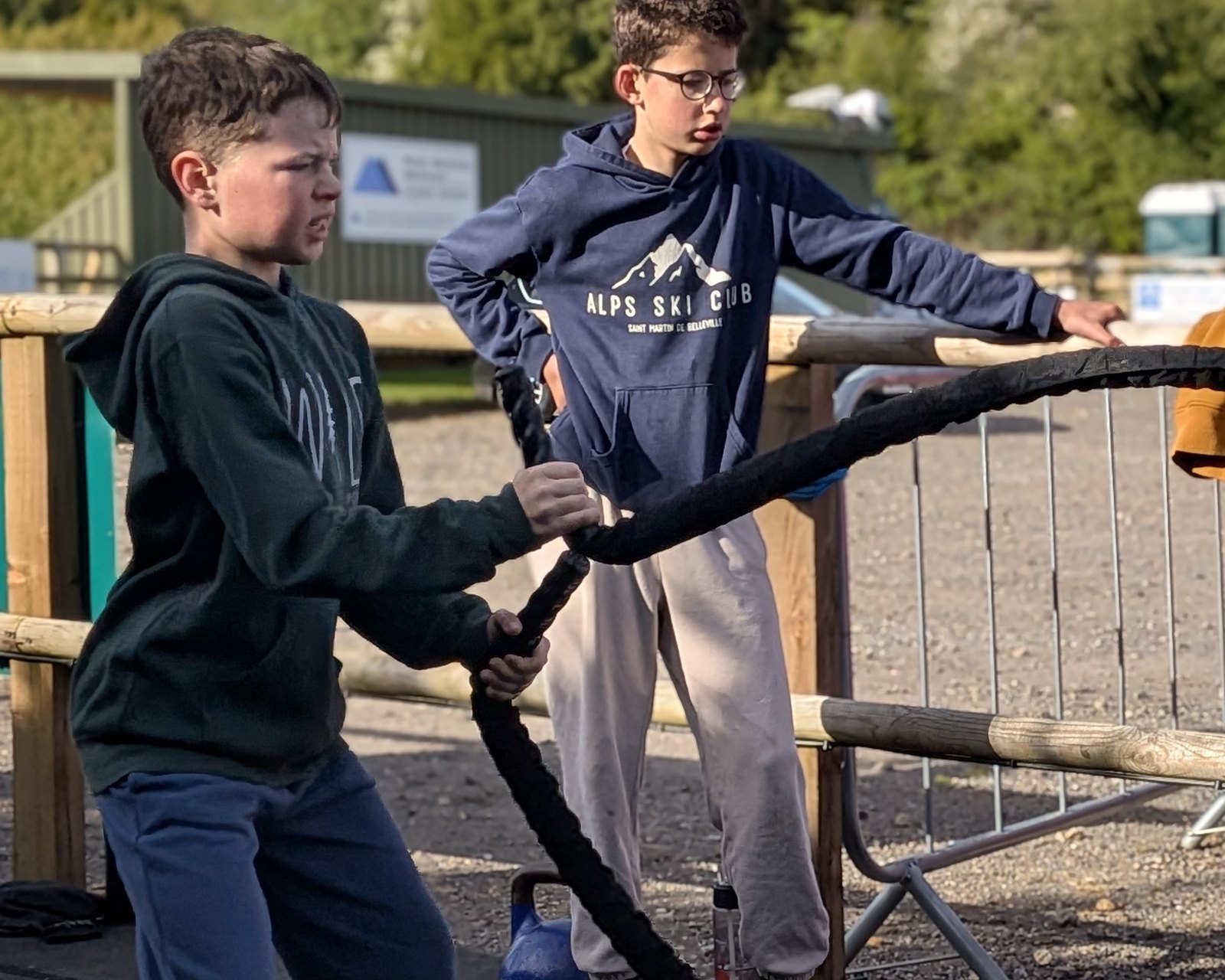 Two teenagers working battle ropes on the outdoor training area